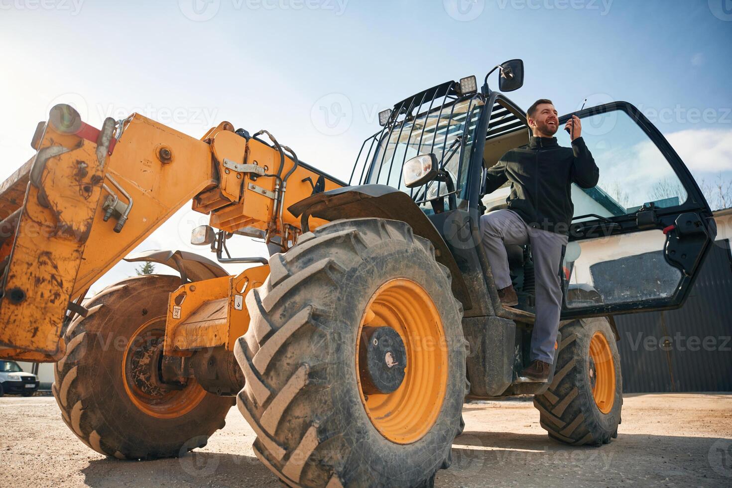 View ,from below, using walkie talkie. Man is with tractor. Agricultural worker photo