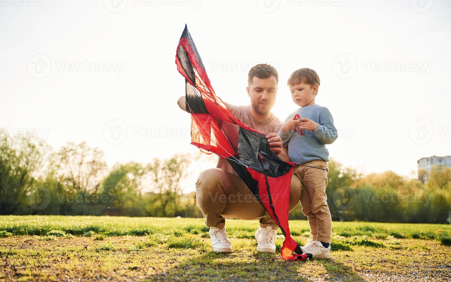 Red,kite. Happy father ,with son are having fun on the field at summertime photo