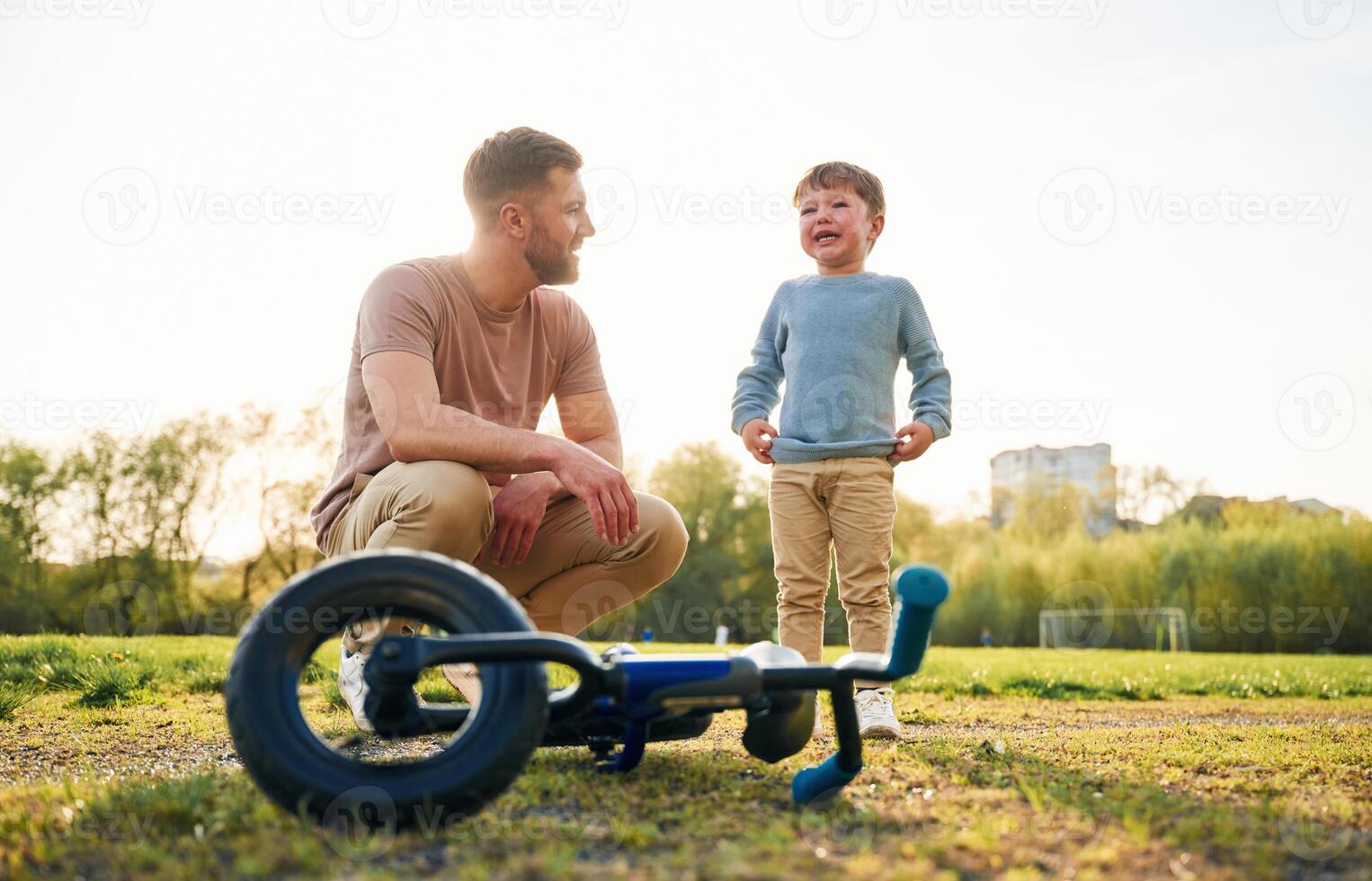 Little, bicycle. Happy father with son are, having fun on the field at summertime photo