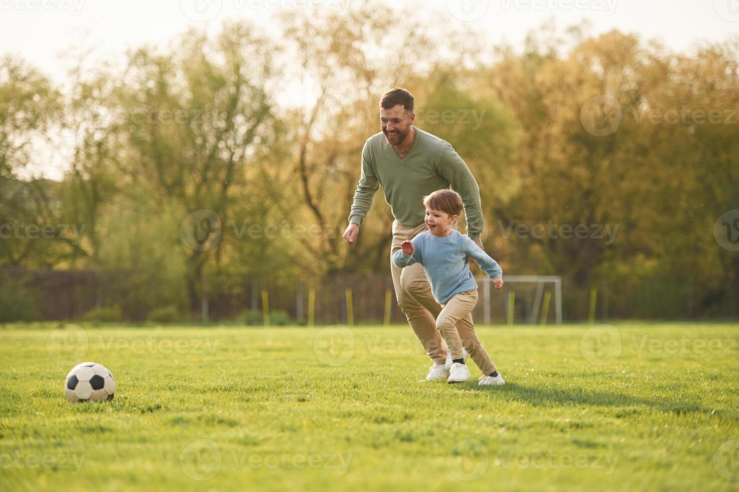 With ,soccer ball. Happy father ,with ,son are having fun on the field at summertime photo