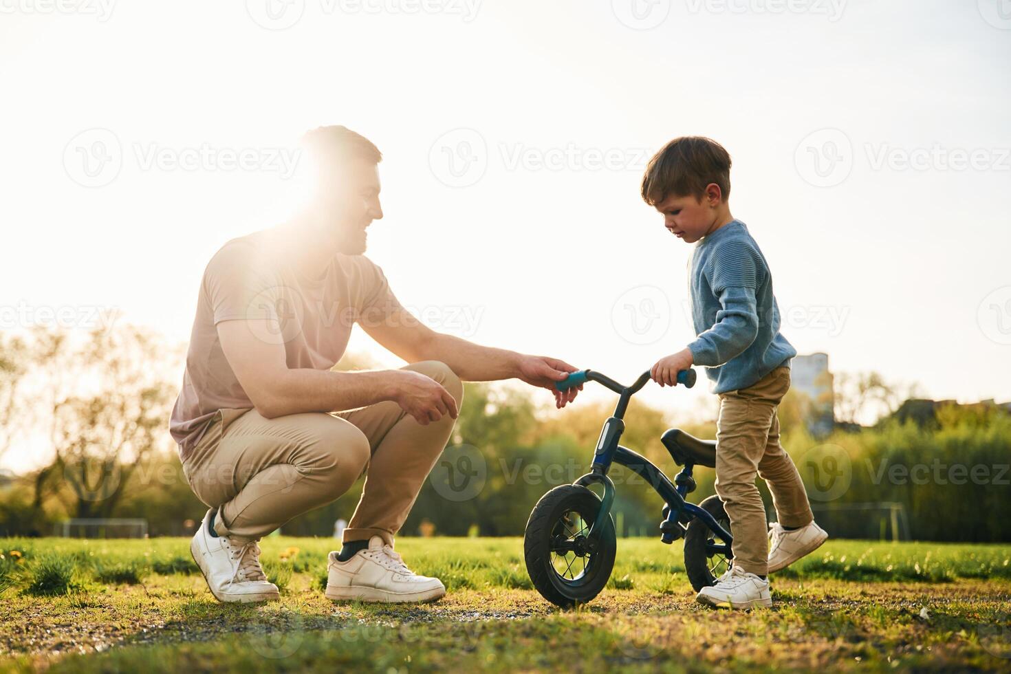 Little bicycle. Happy father with son are ,having fun on the field at summertime photo