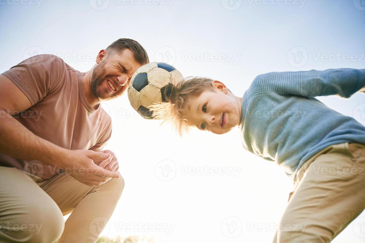 Soccer ball, holding ,it ,by heads, fun. Happy father with son are on the field at summertime photo