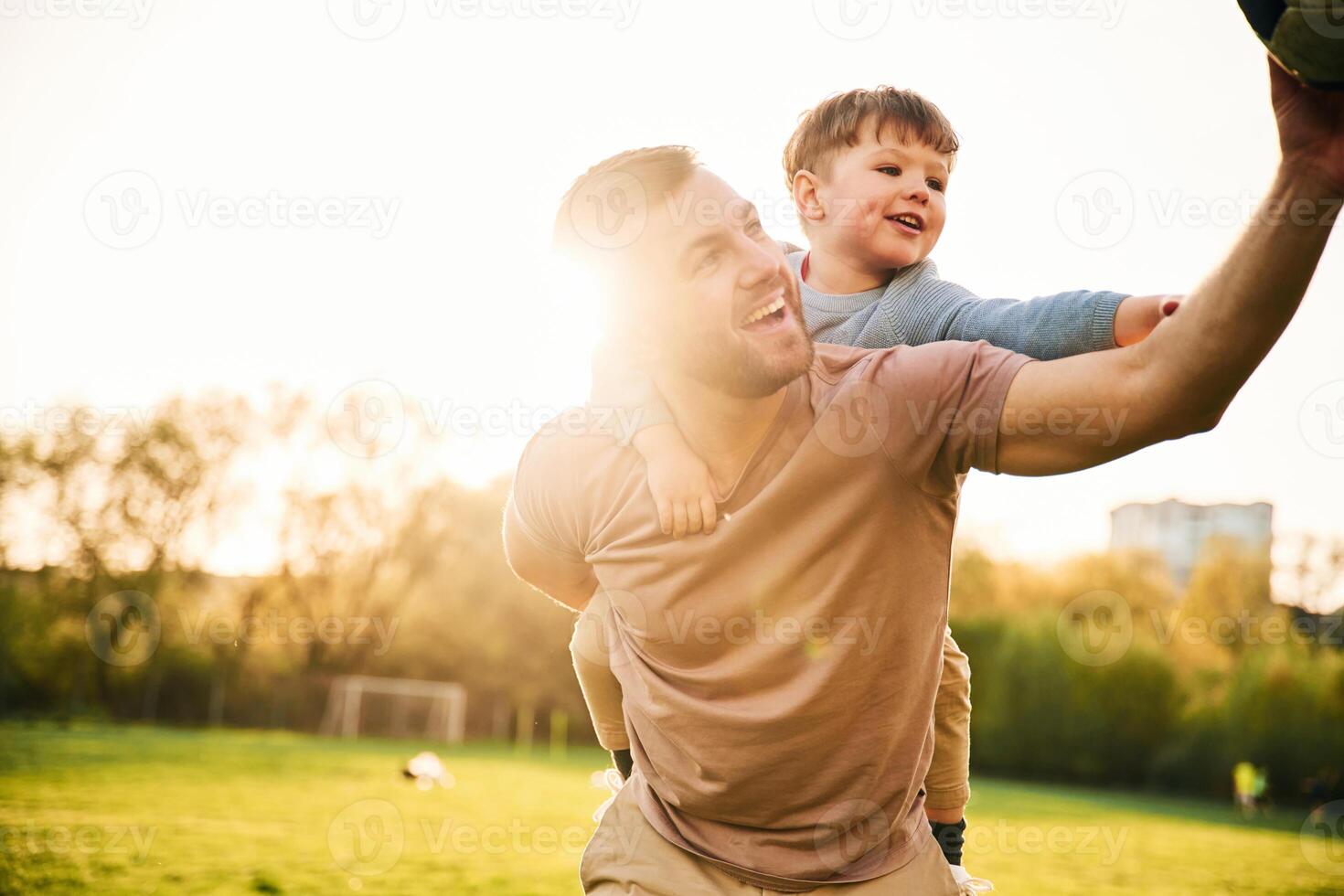 On ,shoulders, with soccer ball. Happy,, father with son are having fun on the field at summertime photo