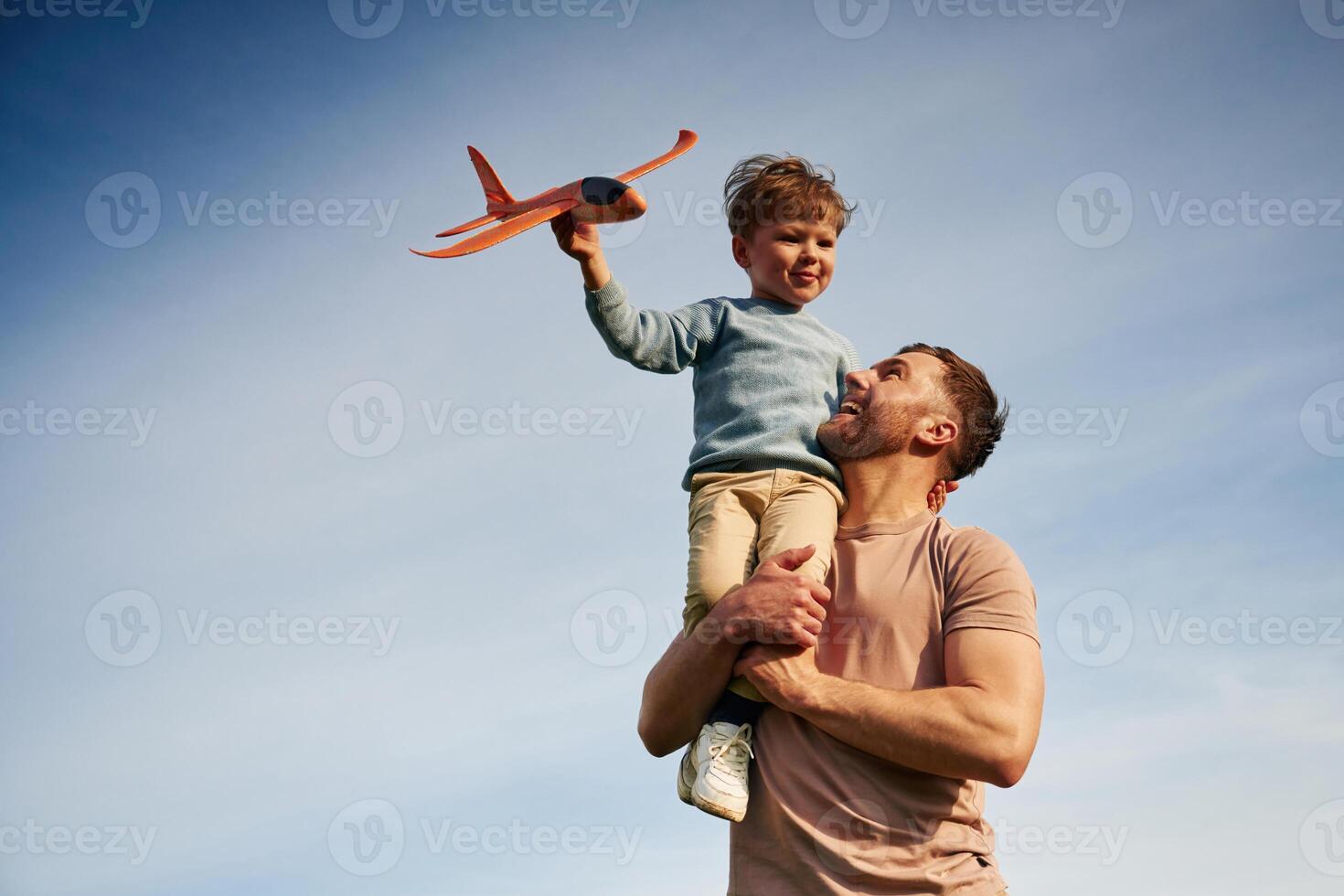 Blue sky with white, cloud. Father is holding son that playing with toy plane photo