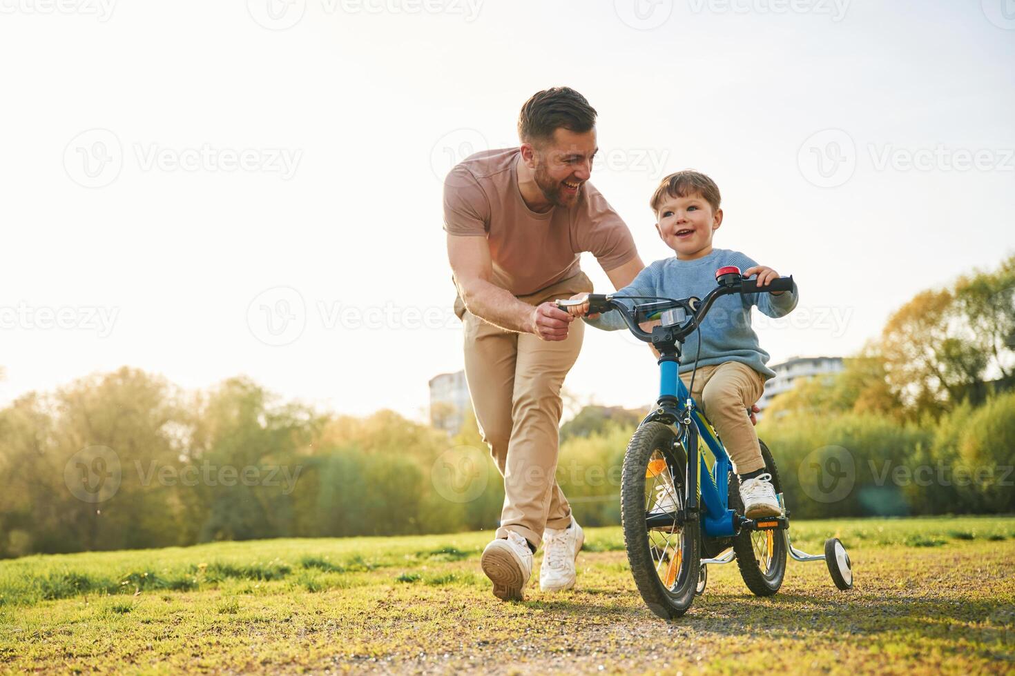 Bicycle, having ,,fun. Happy father with son are on the field at summertime photo