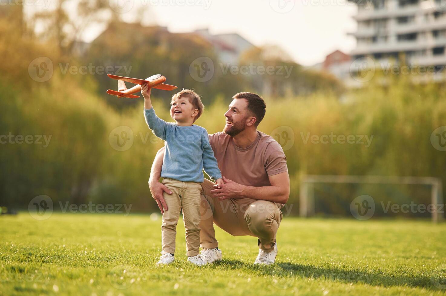 Weekend activities. Playing ,with ,toy plane. Happy father with son are having fun on the field at summertime photo