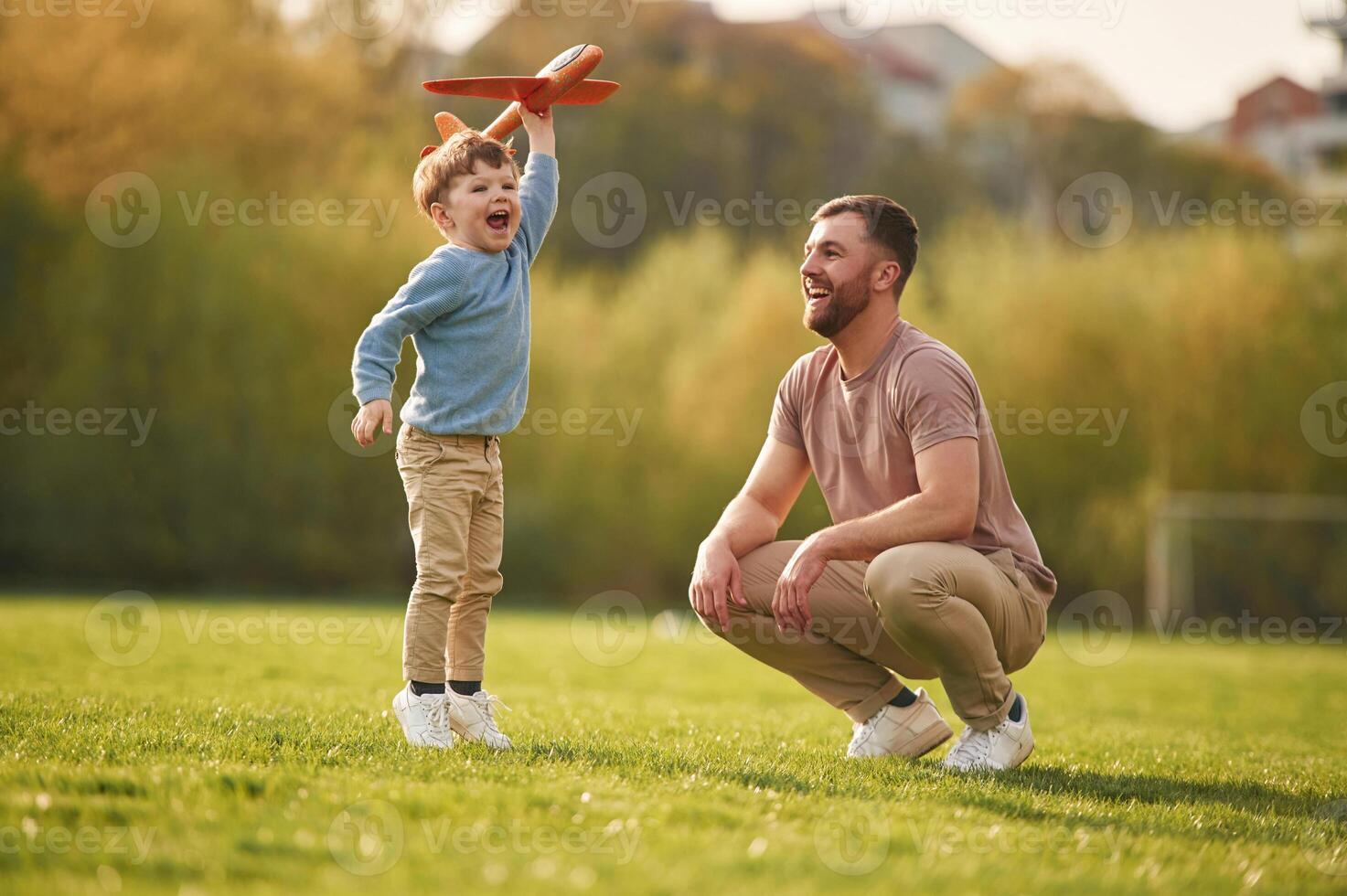 Weekend,, activities. Playing with toy plane. Happy father with son are having fun on the field at summertime photo