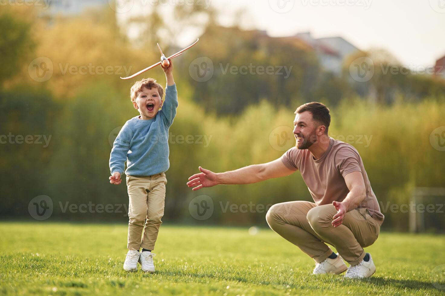 Weekend, activities. Playing with toy plane. Happy father with son are having fun on the field at summertime photo