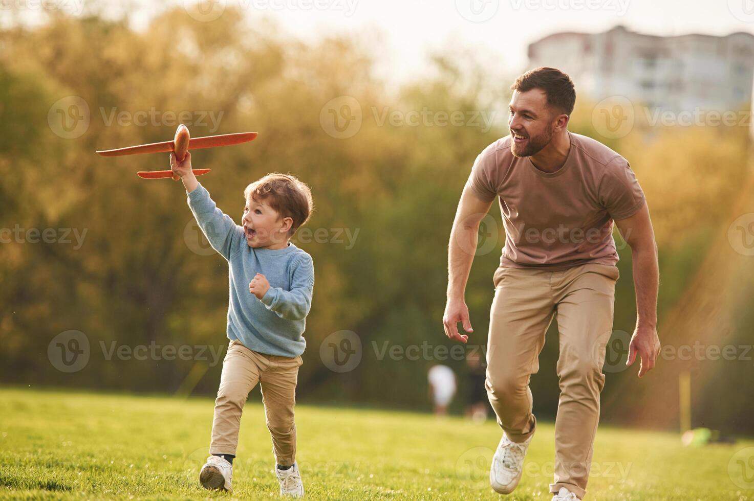Summertime, happiness. Running with toy plane. Father with son are having fun on the field photo