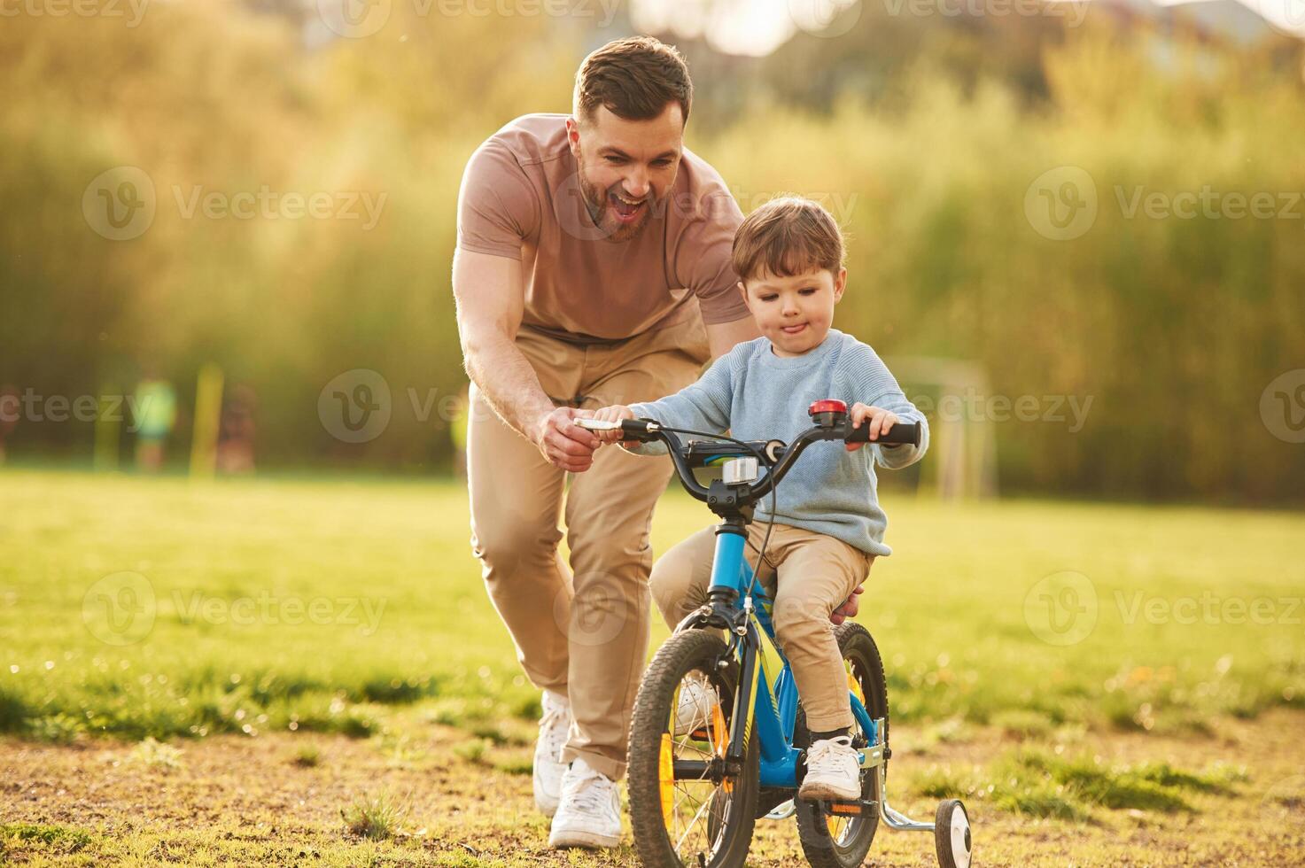 Blue bicycle, riding. Happy father ,with ,son are having fun on the field at summertime photo