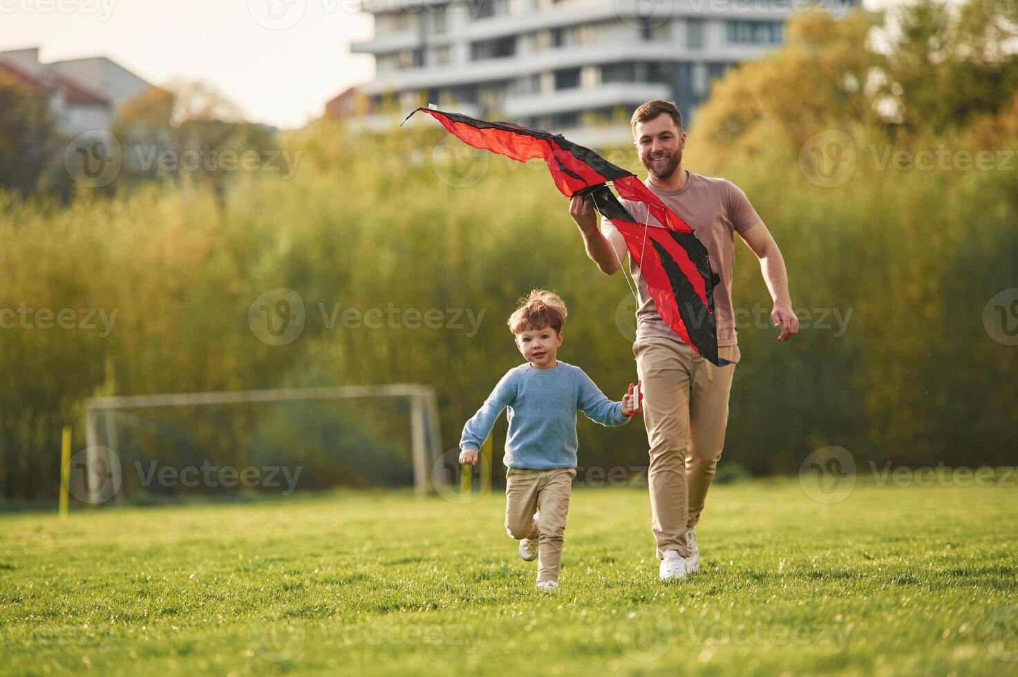 Beautiful red,, kite. Happy father with son are having fun on the field at summertime photo