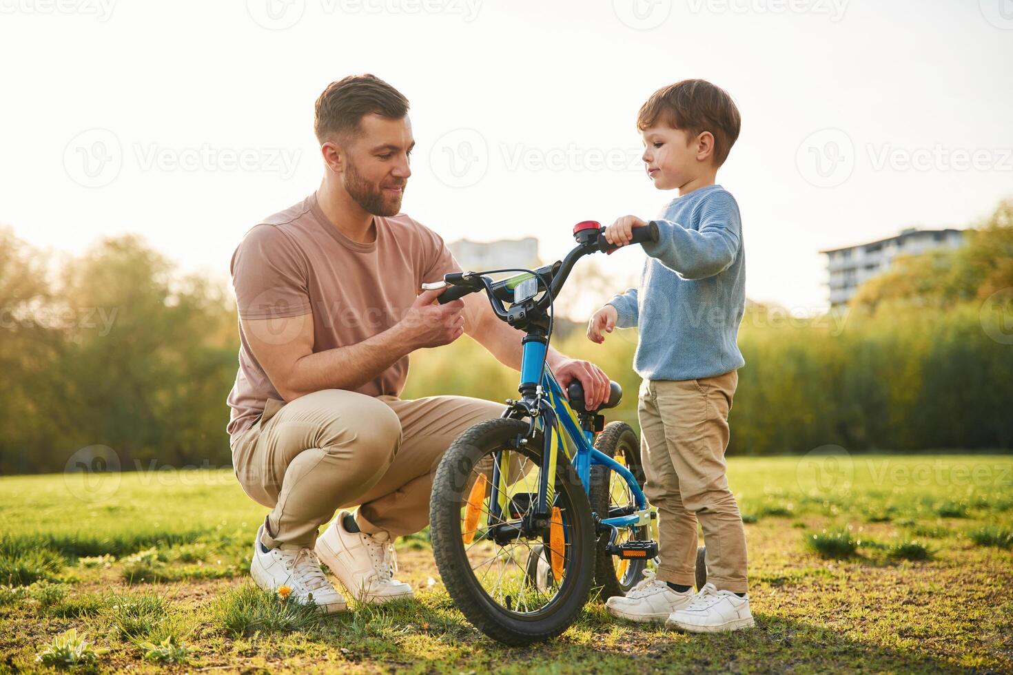 Trying the bicycle. Happy,, father with son are having fun on the field at summertime photo