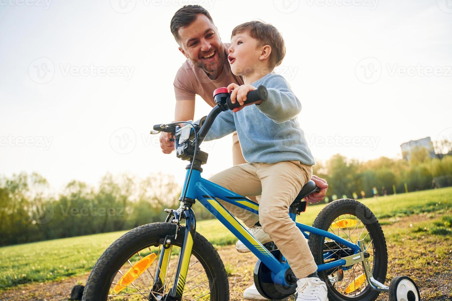 Trying ,,the bicycle. Happy father with son are having fun on the field at summertime photo