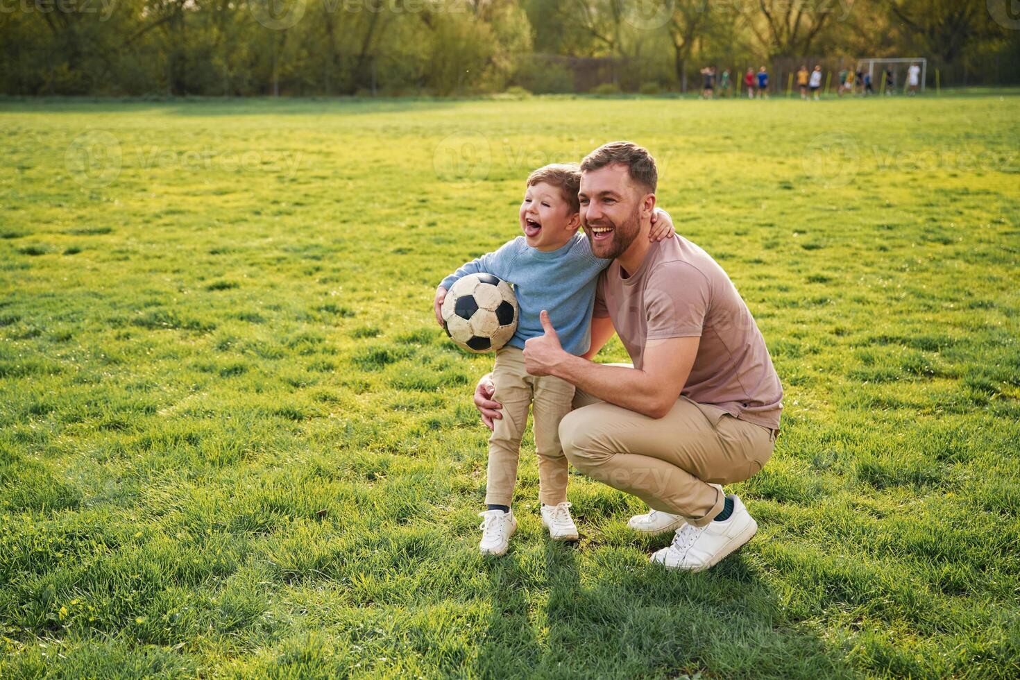 With,, soccer ball. Happy father with son are having fun on the field at summertime photo