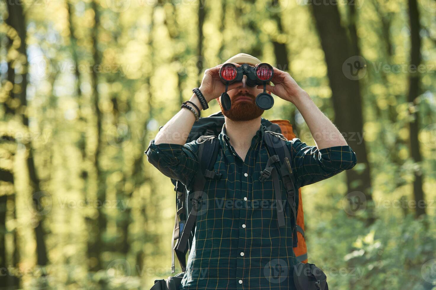 Discovering new place ,with ,binoculars. Bearded man is in the forest at daytime photo