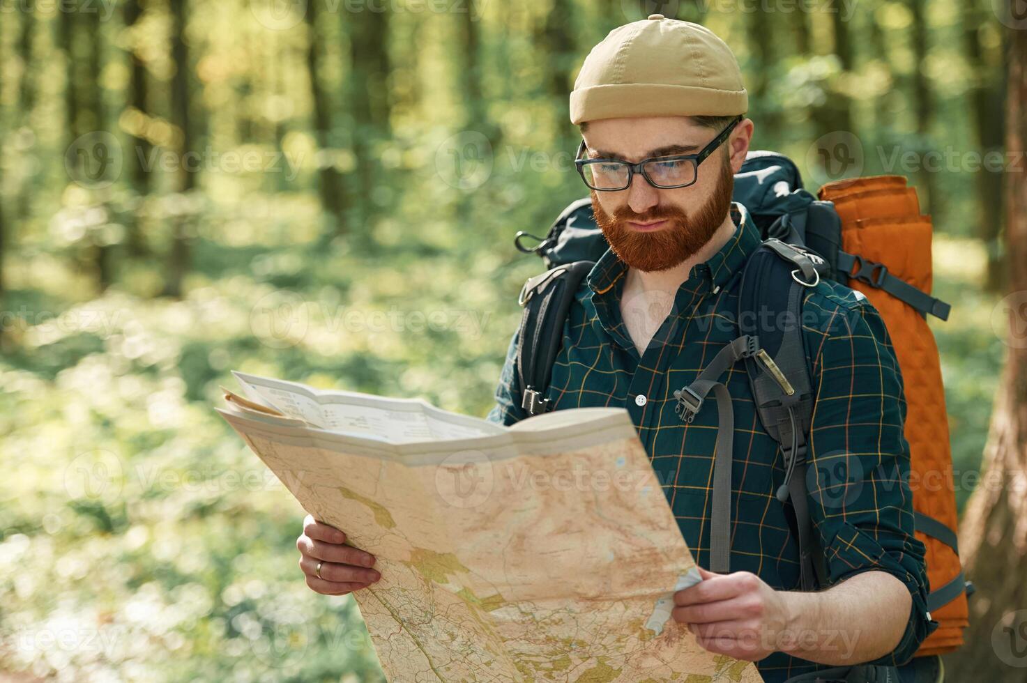 Focused, on, reading the map. Bearded, man is in the forest at daytime photo