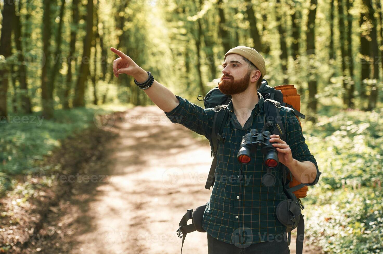 Discovering, new,, place with binoculars. Bearded man is in the forest at daytime photo