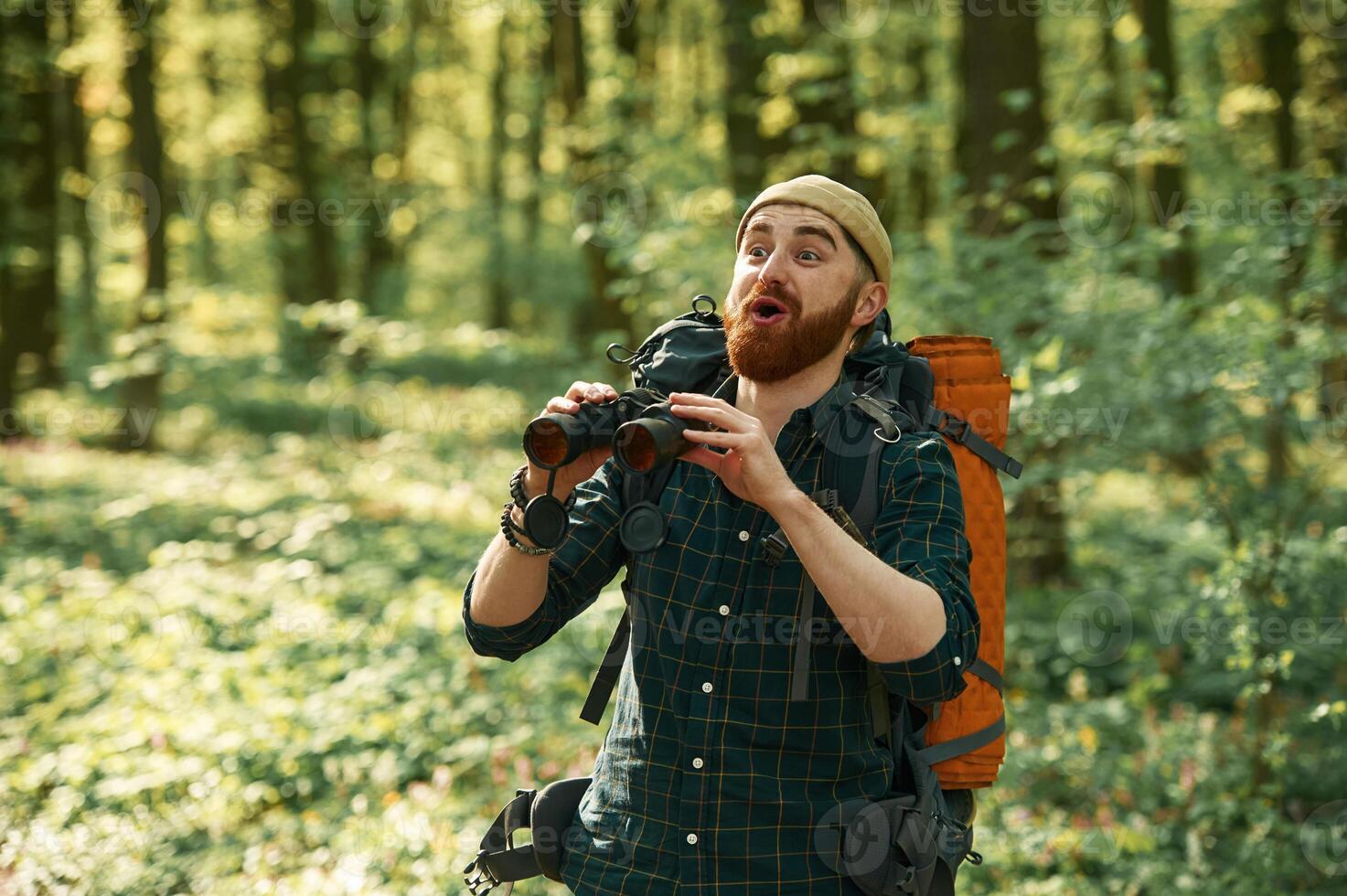 Discovering new place, with, binoculars. Bearded man is in the forest at daytime photo