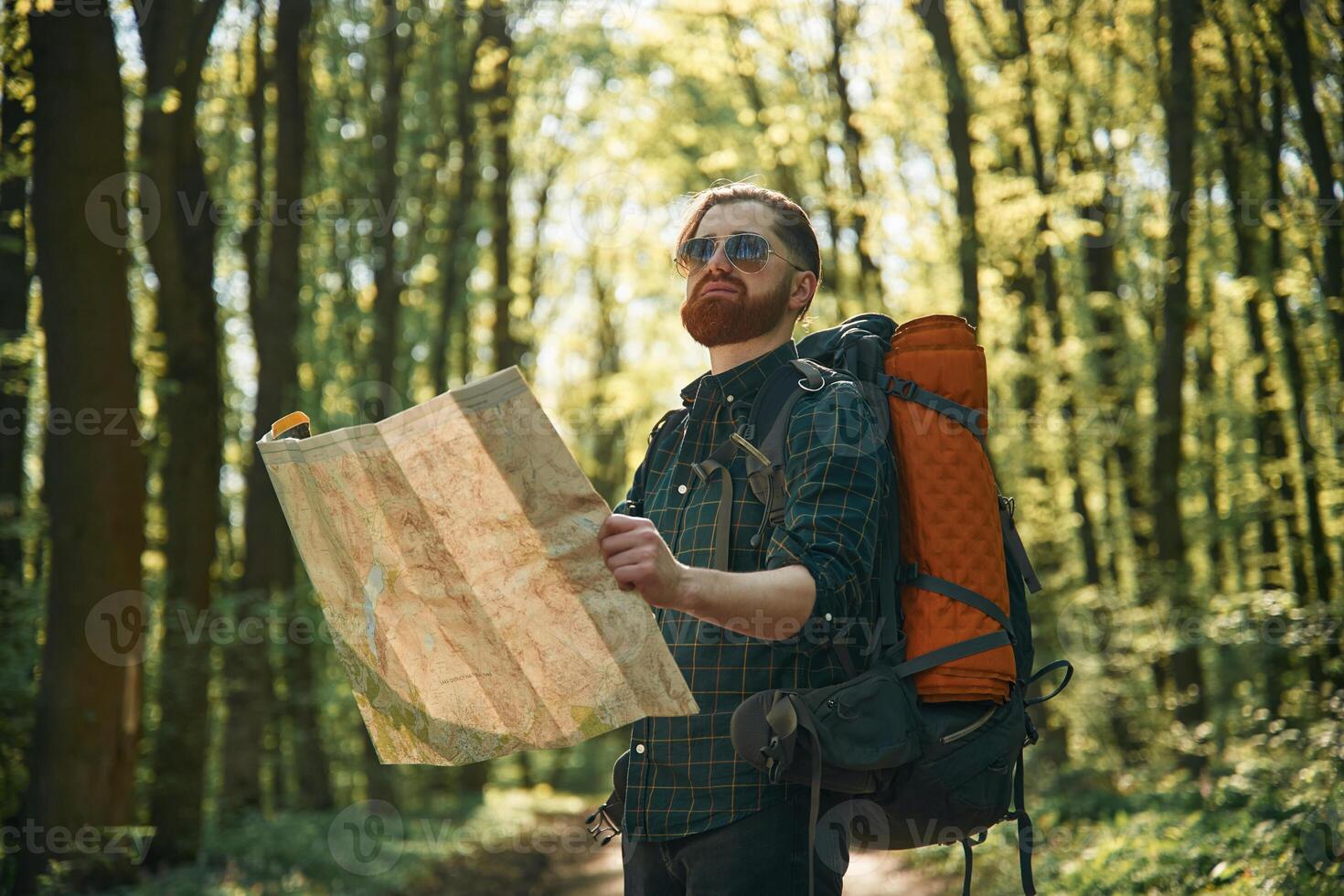 Old fashioned paper map in hands. Bearded ,man is in the forest at daytime photo