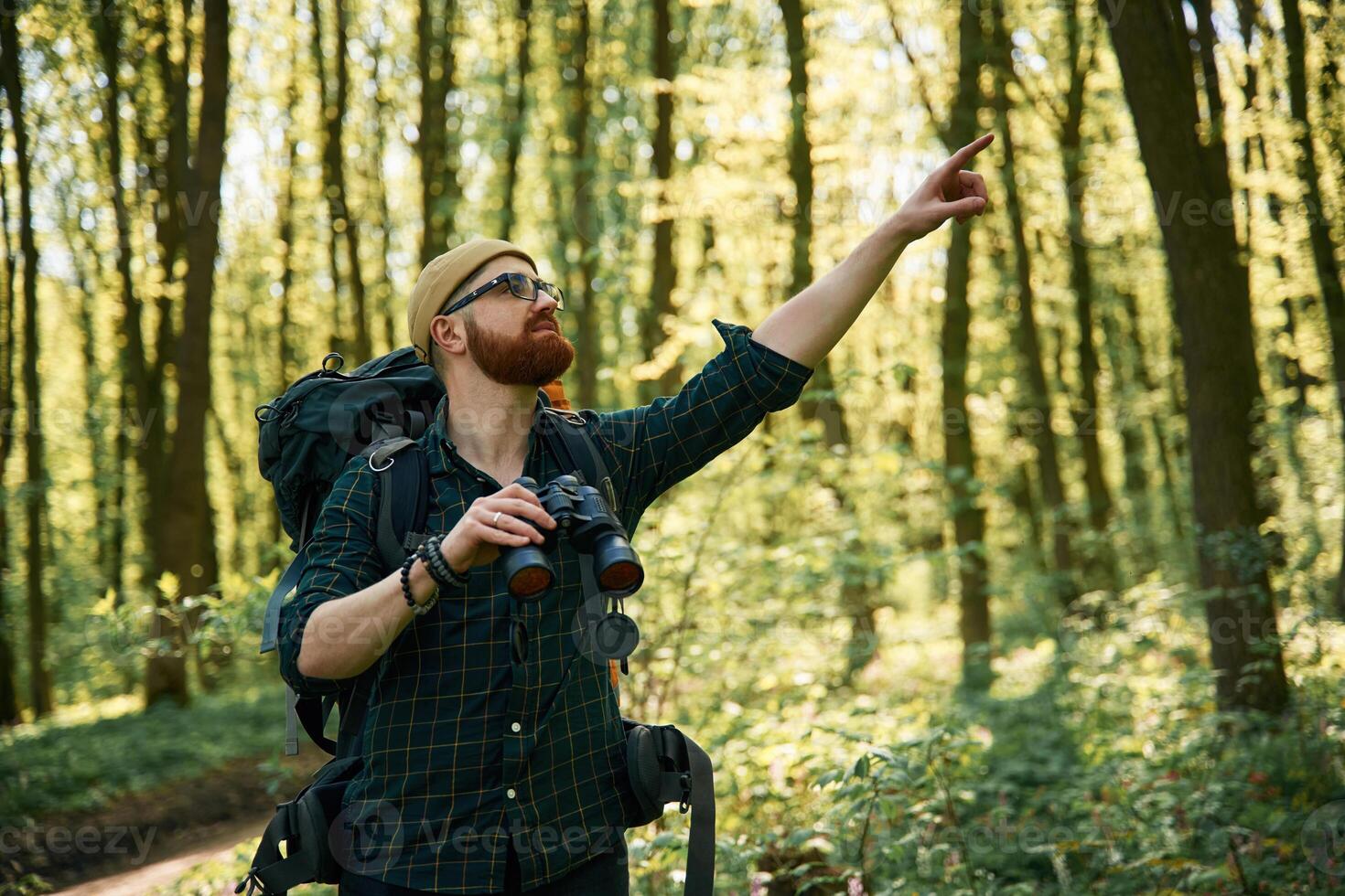 Tourist, with binoculars. Bearded man is in the forest at daytime photo