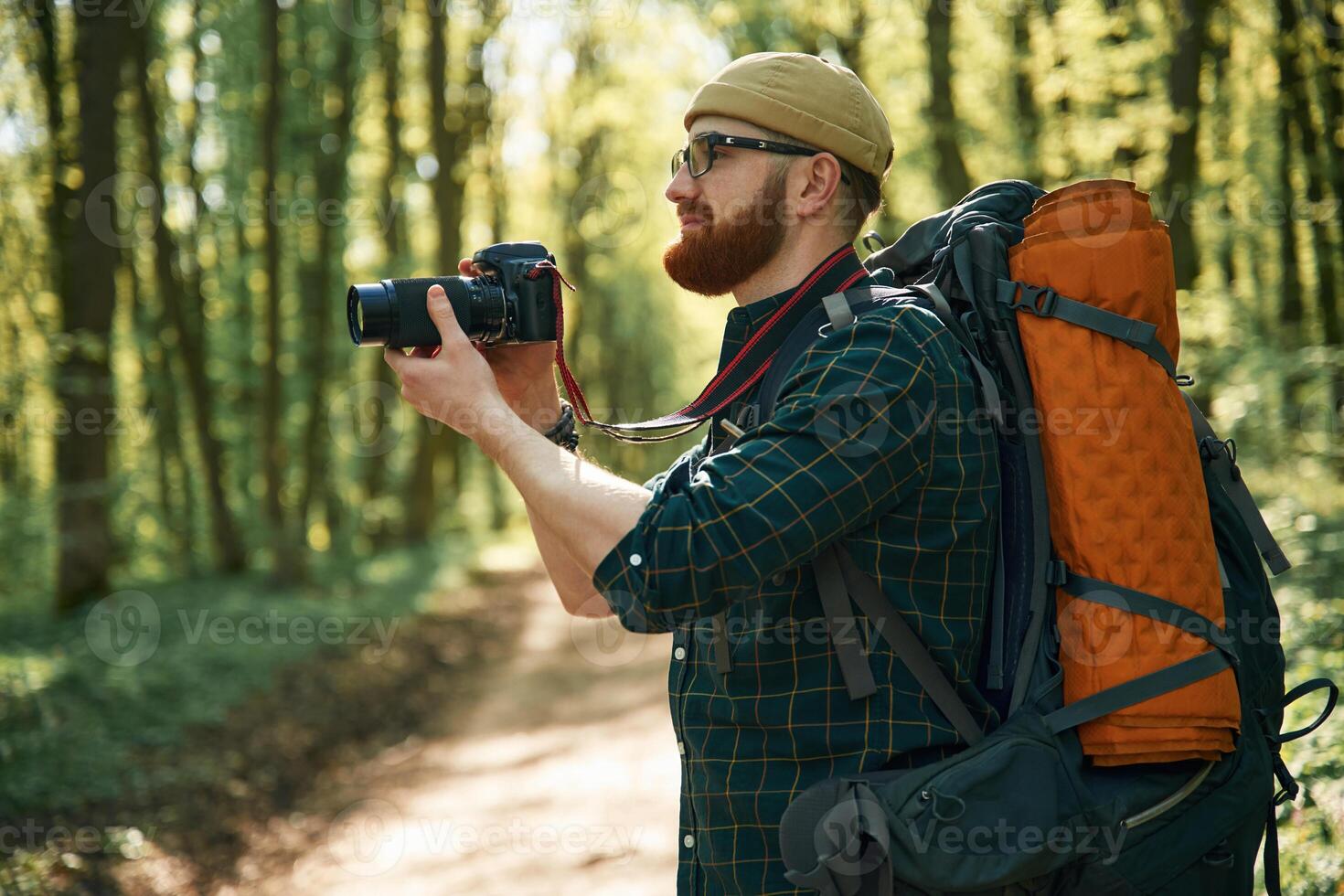 Photographer, with camera. Bearded ,man is in the forest at daytime photo