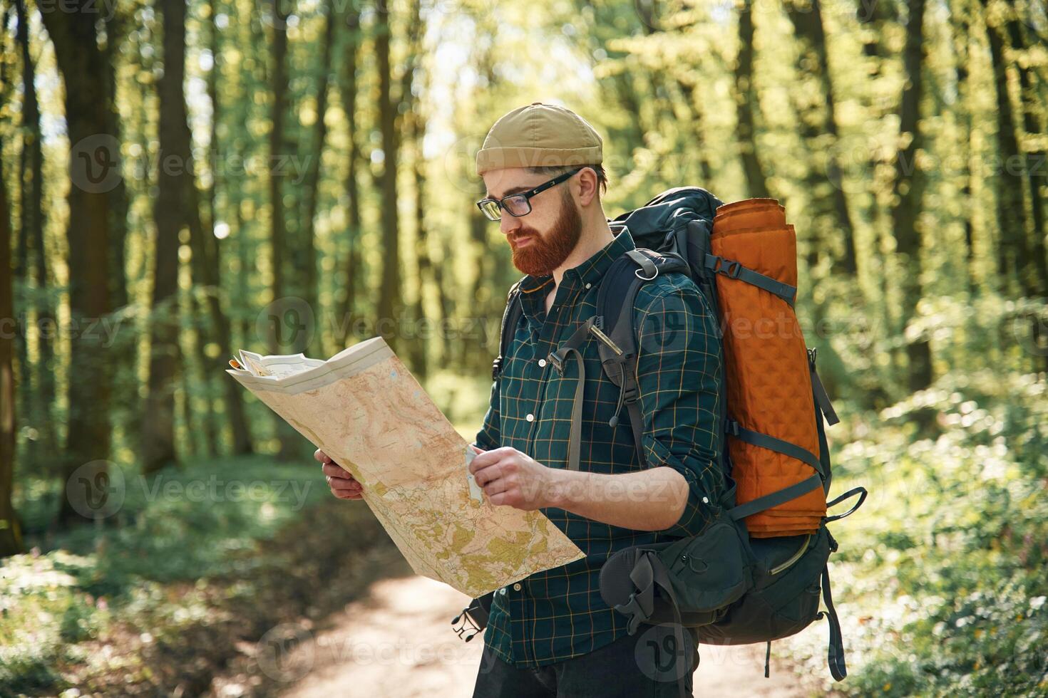 Reading, the, map, looking for a way. Bearded man is in the forest at daytime photo