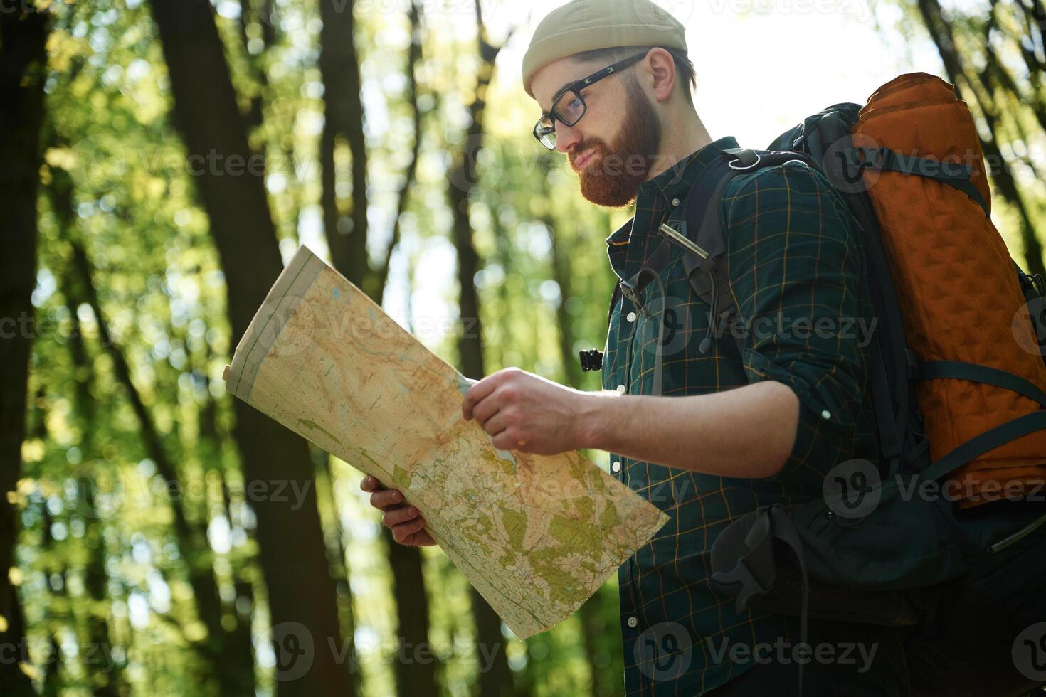 Big paper,, map. Bearded man is in the forest at daytime photo