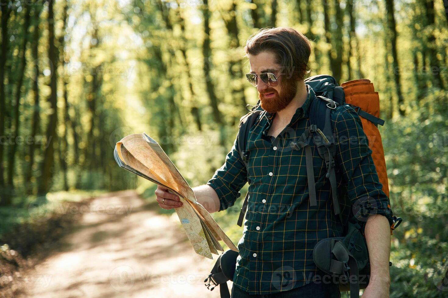 Using ,,the map. Bearded man is in the forest at daytime photo