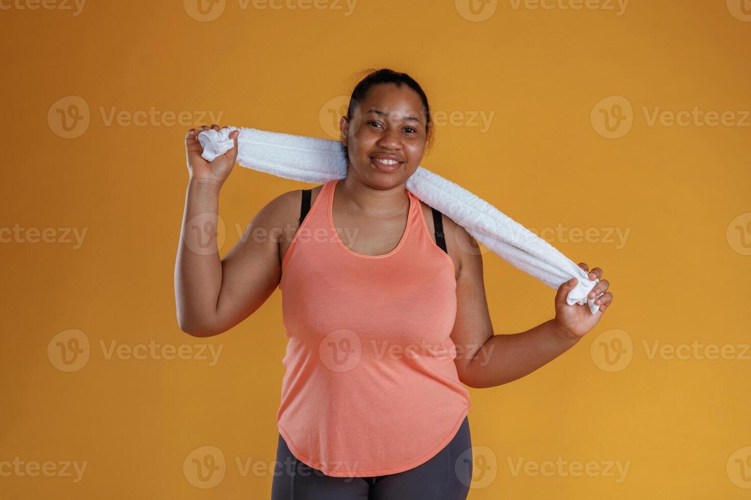 With white ,towel, after exercise. African ,American woman is in the studio against yellow background photo