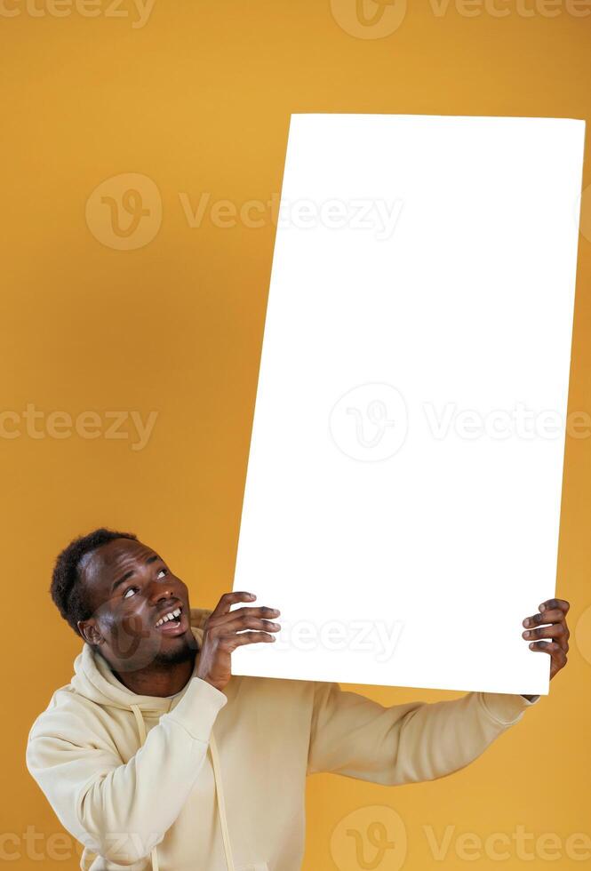 Big copy space piece in hands, shocked. Black guy is against yellow background photo
