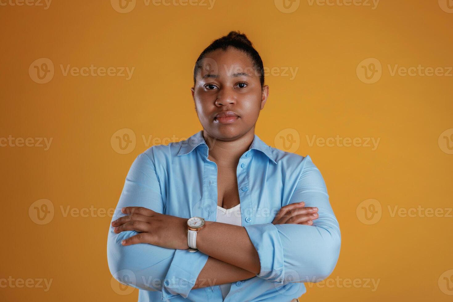 Business ,person, in blue shirt and creamy pants. African American woman is in the studio against yellow background photo