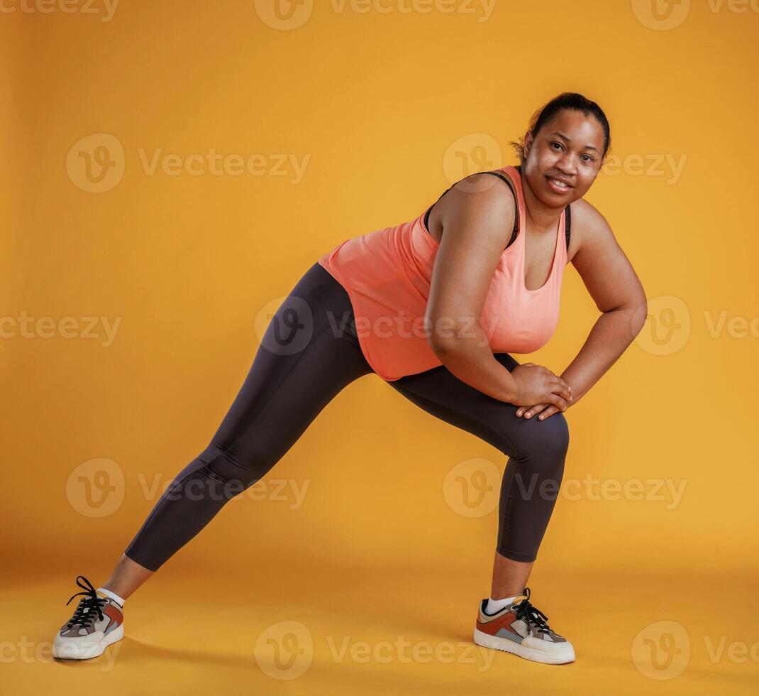 Doing fitness. African, American woman is in the studio against yellow background photo