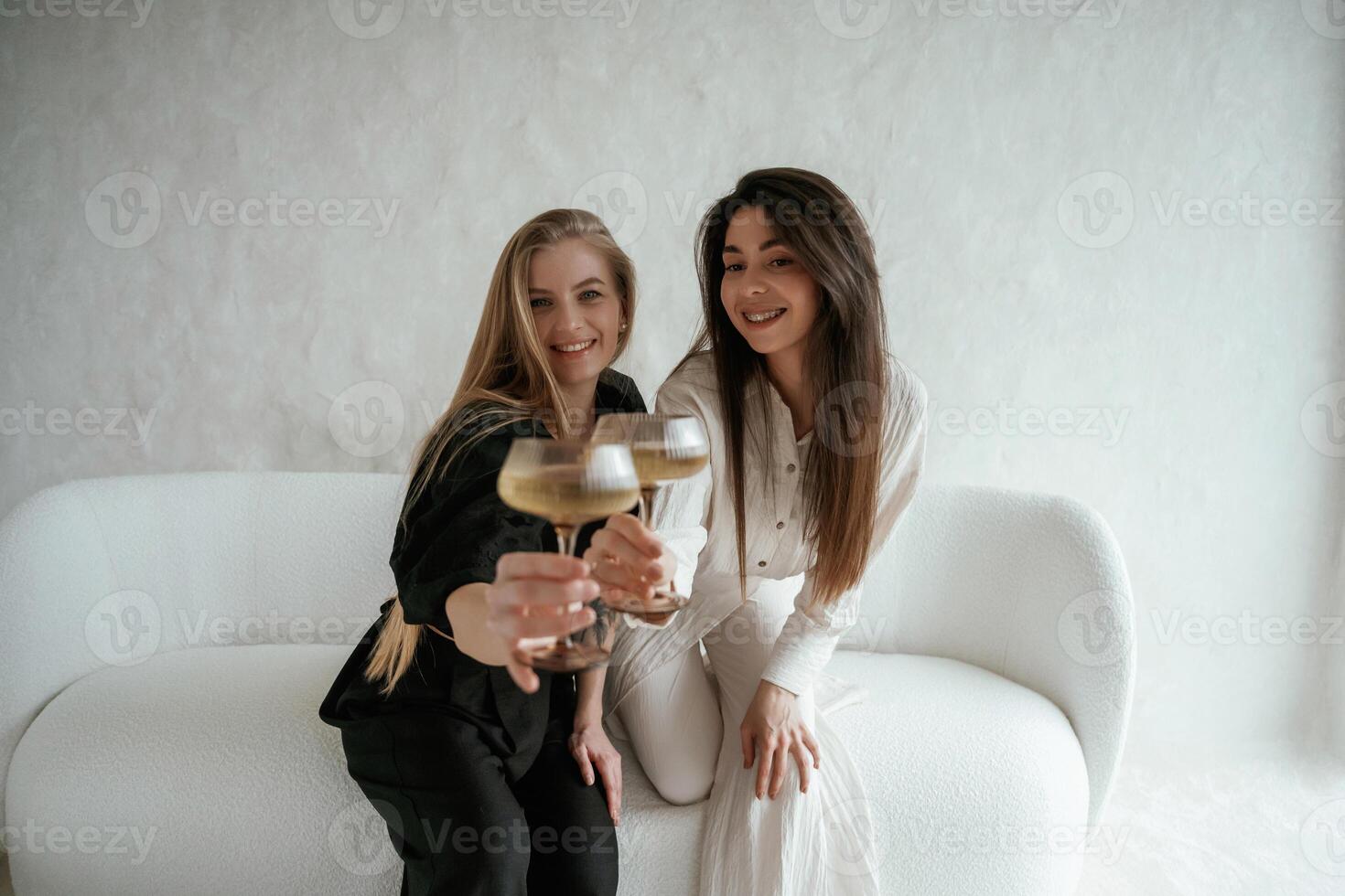 In black, and ,,white clothes, with drink, celebrating. Two happy young female best friends are indoors photo