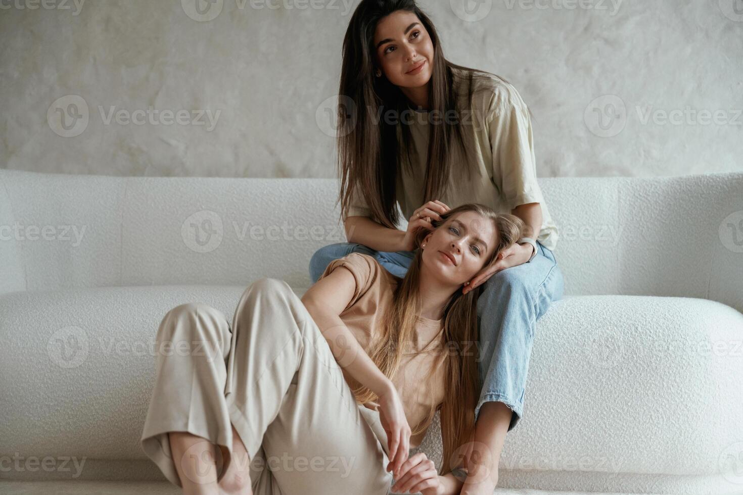 Looking forward,,, sitting. Two happy young female best friends are indoors photo