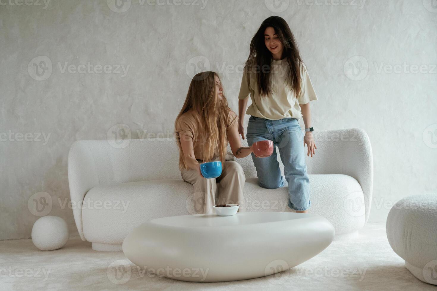 Looking, forward,, sitting. Two happy young female best friends are indoors photo