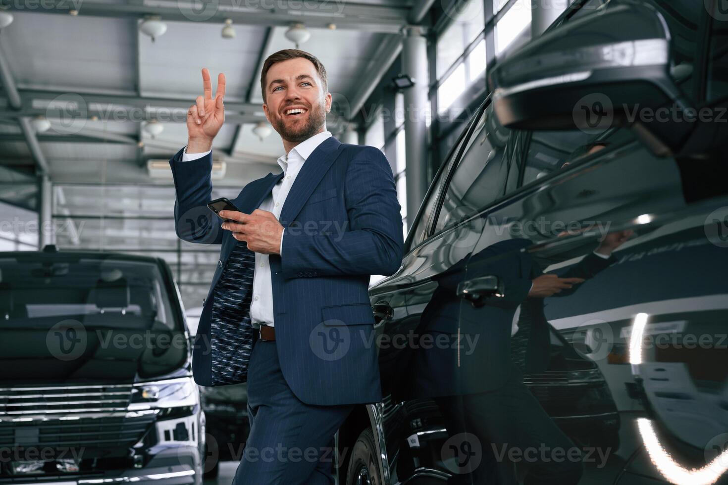 Peace hand gesture. A businessman is in a car dealership photo