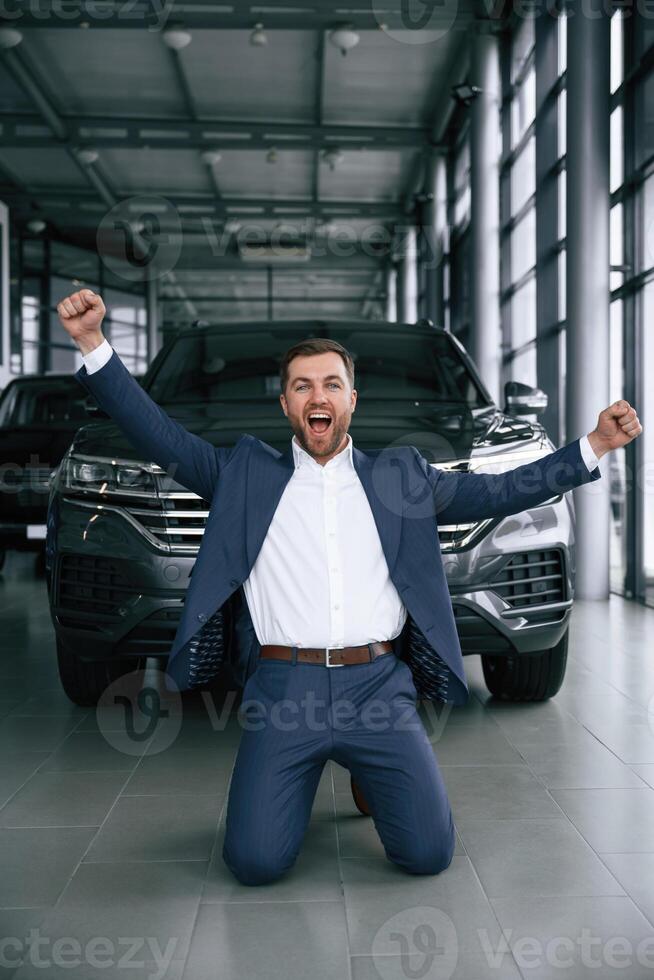 Happy new owner of automobile... A, businessman is in a car dealership photo
