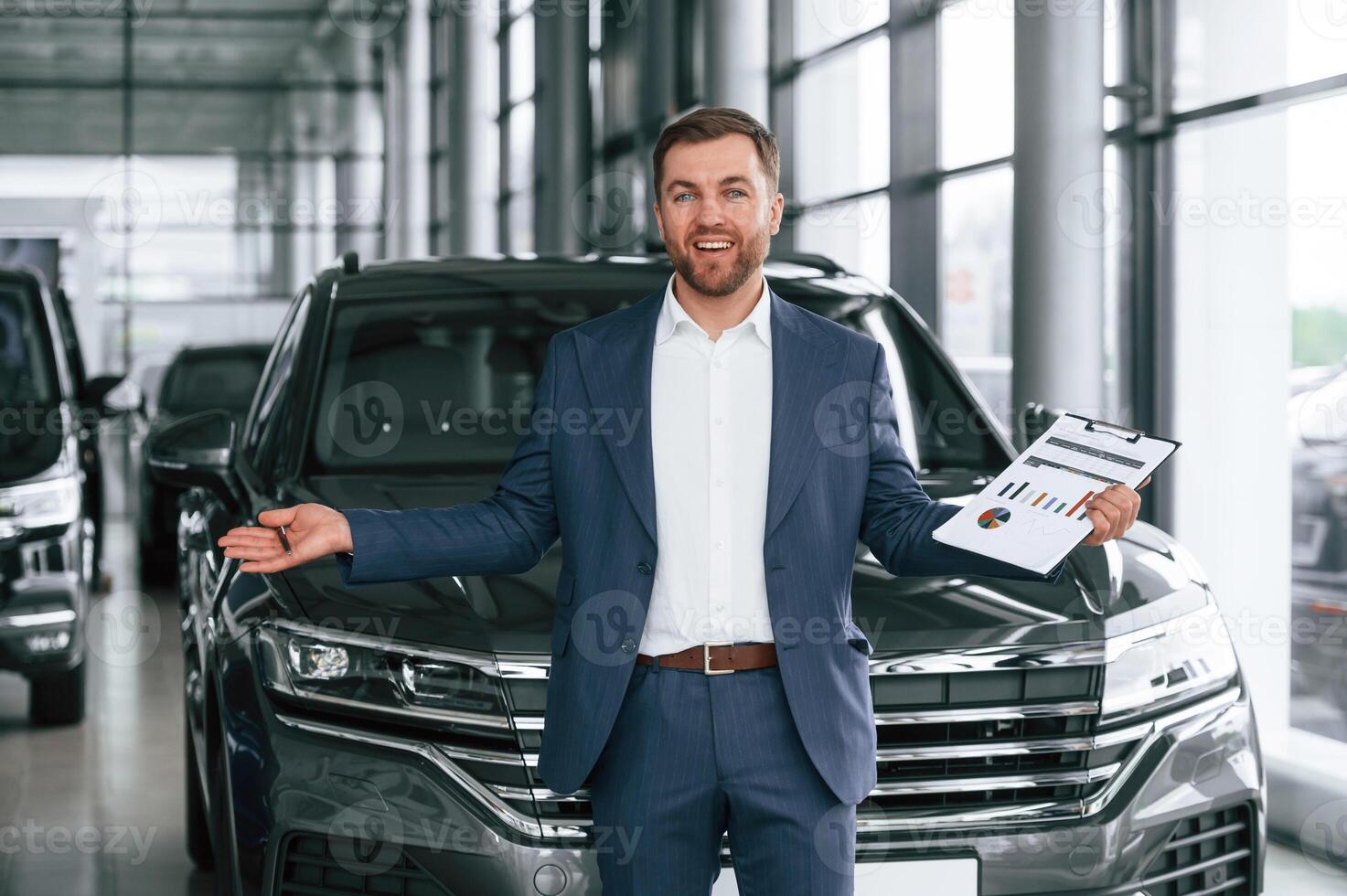 With notepad... A businessman is in a car dealership photo