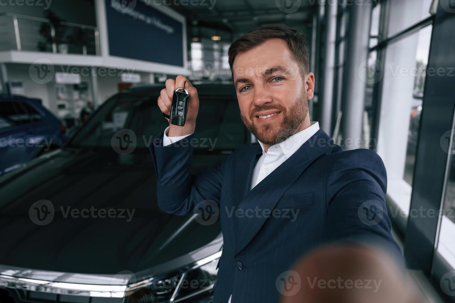 Happy new owner of automobile.. A businessman is in a car dealership photo