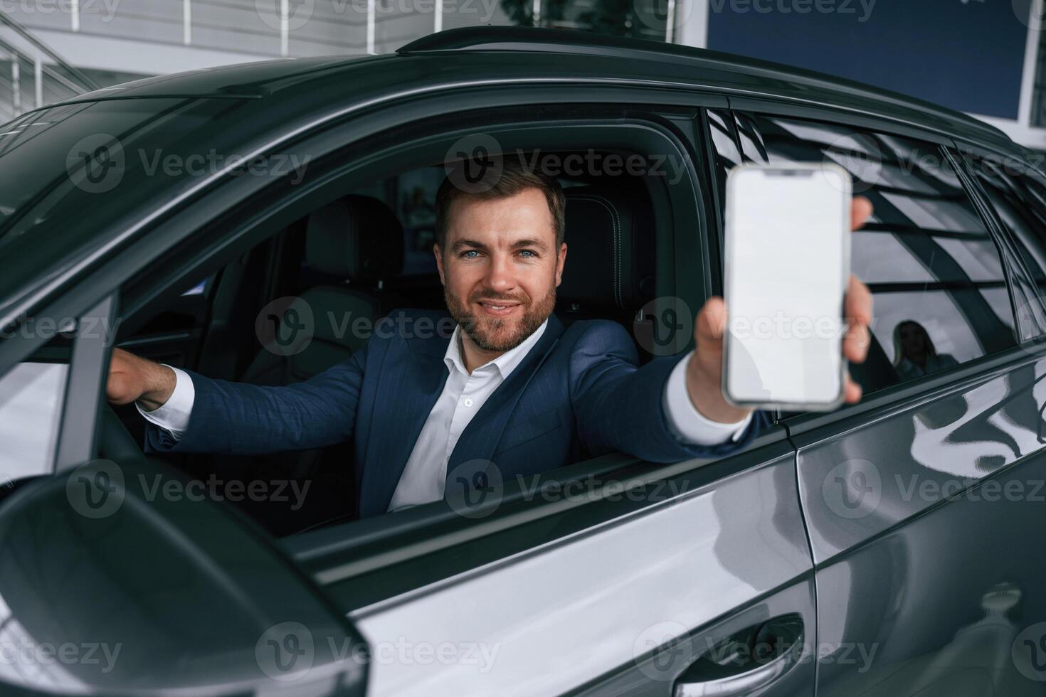 Smartphone with,, copy space on display. Businessman is in the brand new car photo