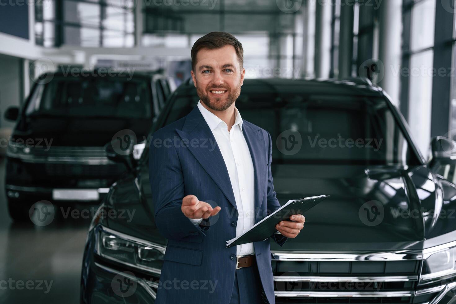 Cheerful, salesman. Guy is in a car dealership photo