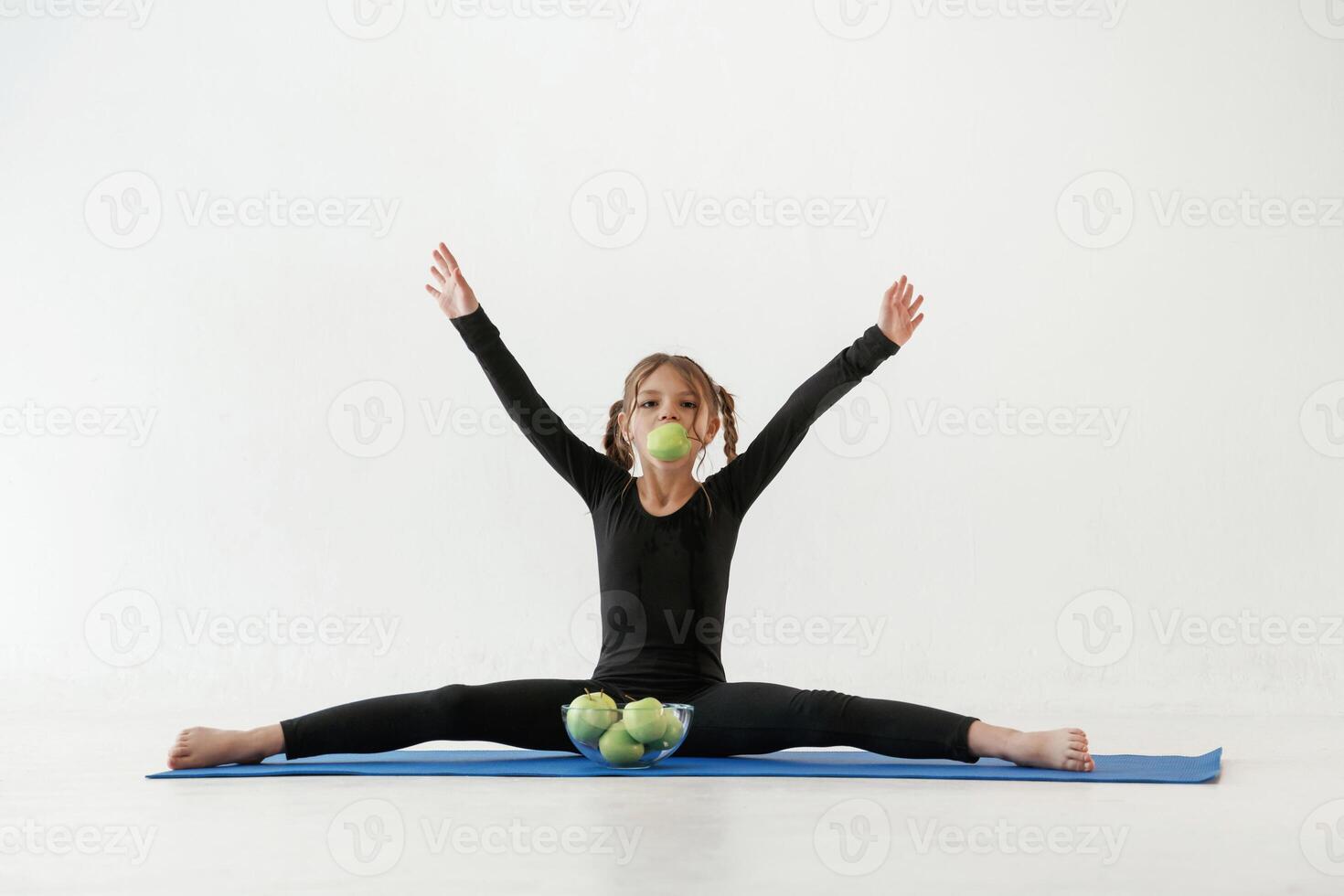 Healthy eating, green,, apples. Little girl in yoga clothes is on the fitness mat photo