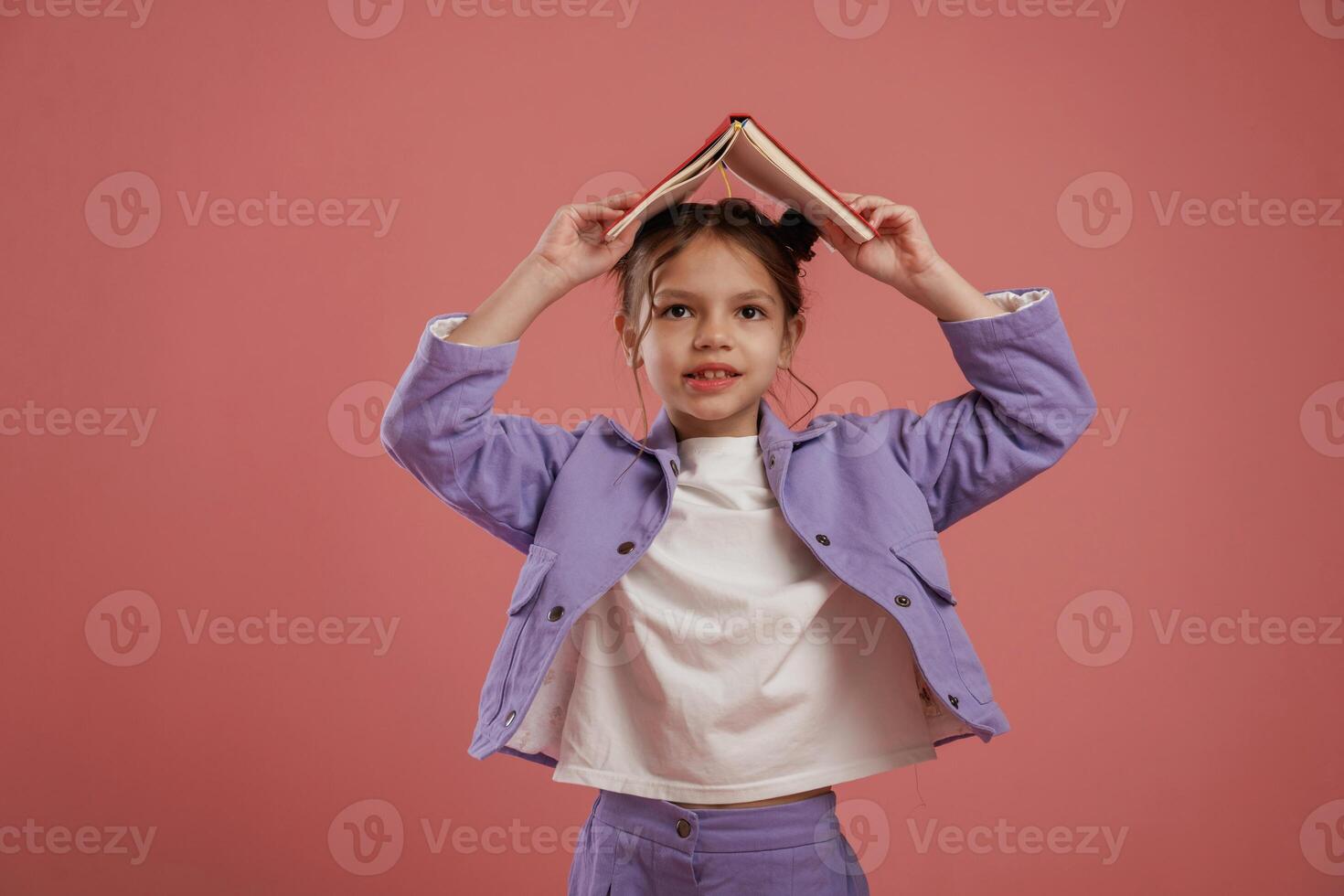 Notepad or book, conception ,of education. Cute little girl is against pink background photo