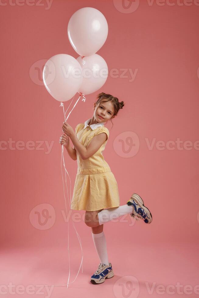 Birthday party. Holding balloons. Cute little ,girl is against pink background photo