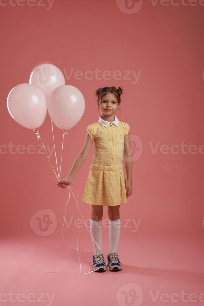 Bunch of balloons, party. ,Cute ,little, girl is against pink background photo