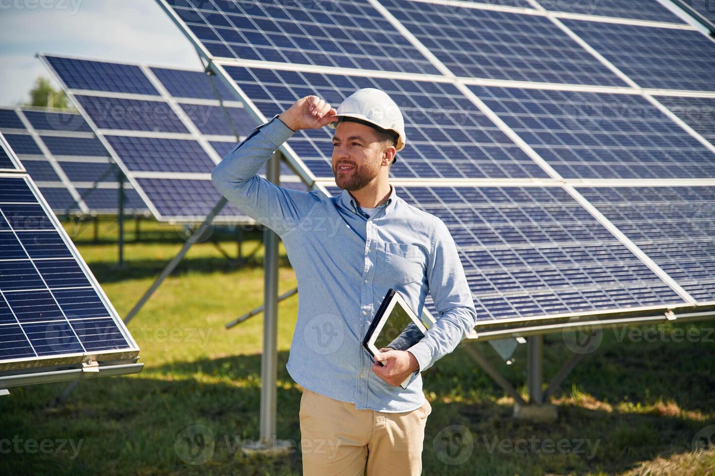 Digital ,tablet,, in hand. Engineer with photovoltaic solar panels outdoors at daytime photo