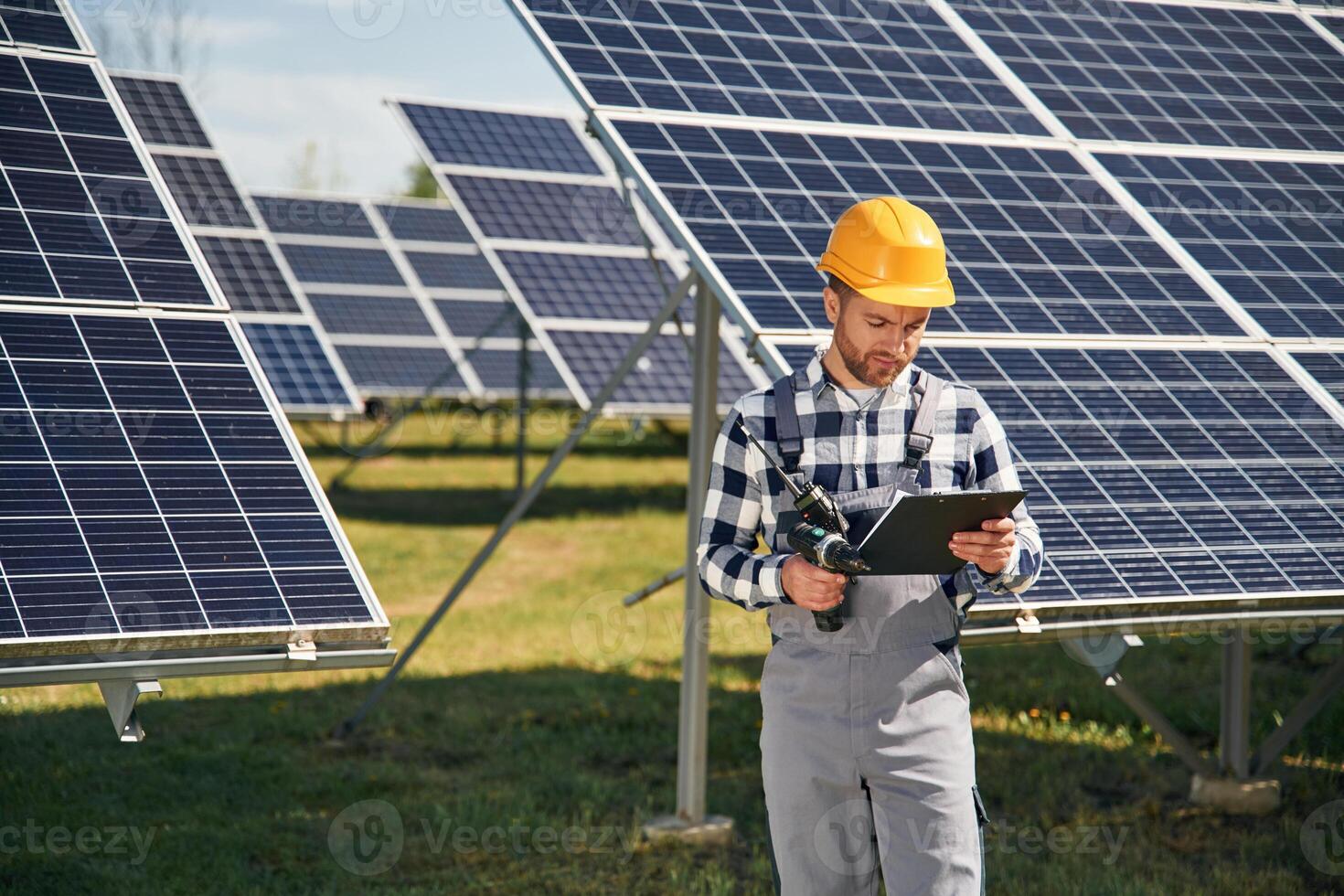 On, the field with, notepad in hands. Engineer with photovoltaic solar panels outdoors at daytime photo