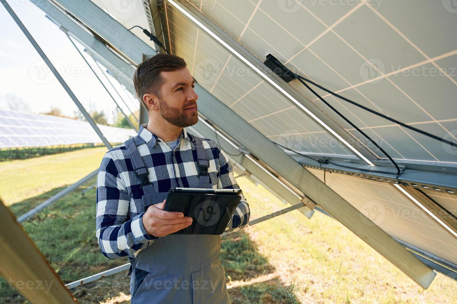 Under the photovoltaic solar panel, and, with digital tablet. Engineer outdoors at daytime photo