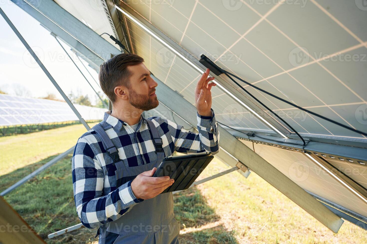 Under the ,photovoltaic solar panel and with digital tablet. Engineer outdoors at daytime photo