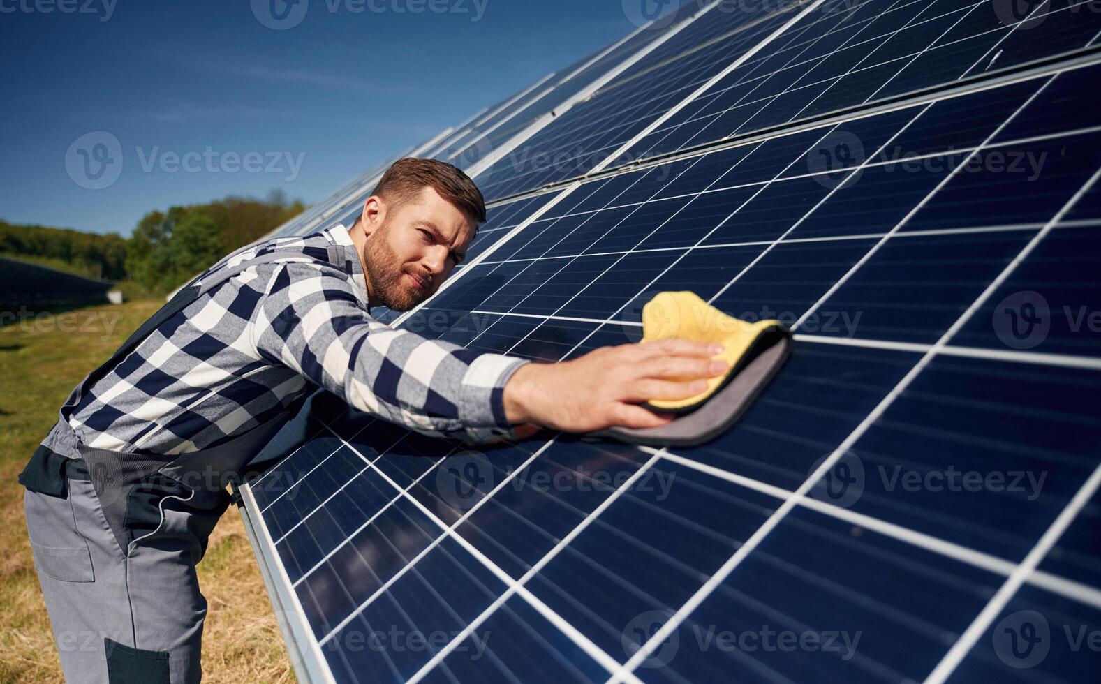 Surface, must ,,me clean. Engineer with photovoltaic solar panels outdoors at daytime photo